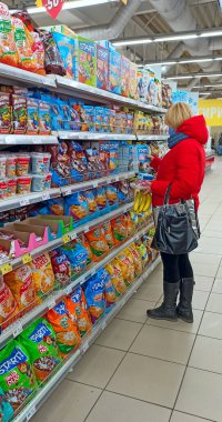 Chernihiv - Ukrayna. 28 Şubat 2020: Kadın süpermarketten mısır gevreği alıyor. Covid-19 karantina dönemindeki bir kadın dükkandaki pulları seçiyor. Maskeli kadın süpermarkette yemek seçiyor..