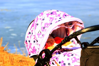 perambulator Nehri yakınında küçük bebek uyur