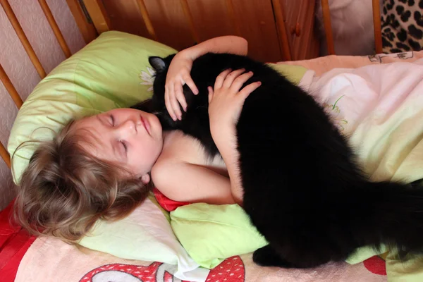 Meisje spelen met haar kat in haar bed — Stockfoto