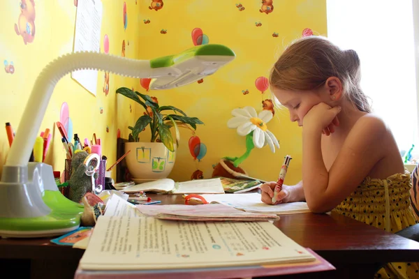 Schoolgirl learns lessons at the table — Stock Photo, Image