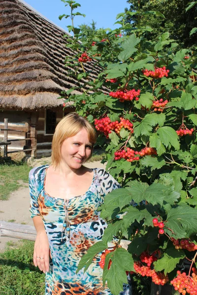 Dívka s Kalina růže kromě venkovský dům — Stock fotografie