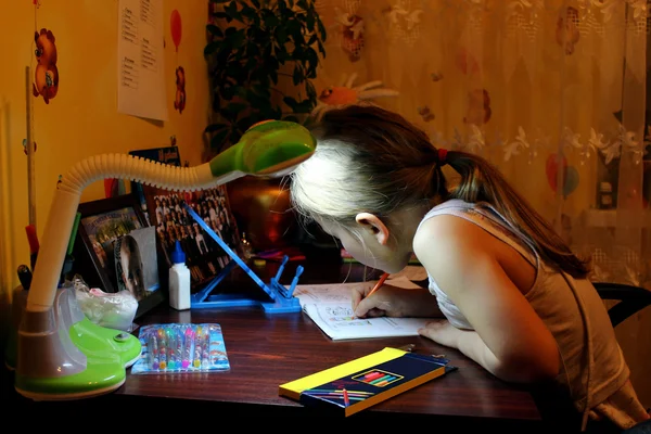 Schoolgirl learns lessons at the table — Stock Photo, Image