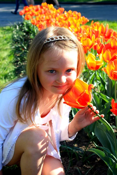 Niña huele tulipanes en el lecho de flores —  Fotos de Stock