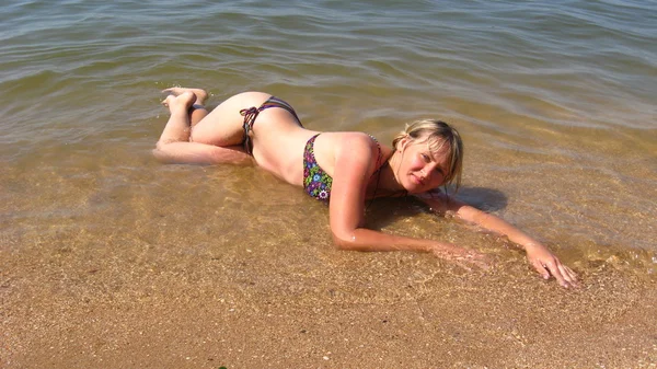 Menina deitado na areia no litoral — Fotografia de Stock