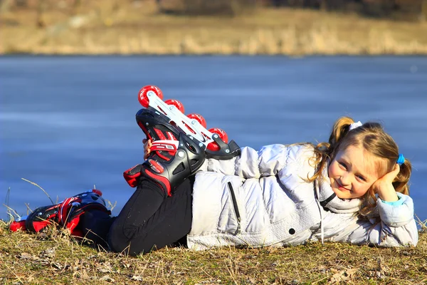 Jovem menina em patins coloca no chão — Fotografia de Stock