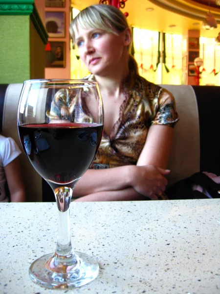 Glass of red wine on the table and a girl — Stock Photo, Image