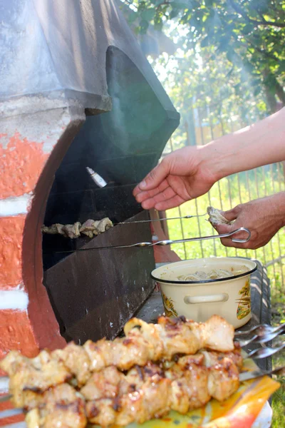 Mãos humanas assar churrasco apetitoso no fogo — Fotografia de Stock