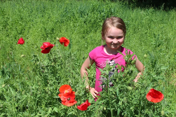 Fille debout dans le lit de fleurs avec des coquelicots rouges — Photo