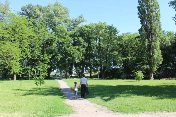 Отец с дочерью отдыхают в парке с большими деревьями — стоковое фото