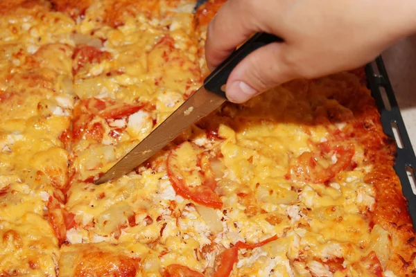 Appetizing home pizza cutting by knife — Stock Photo, Image