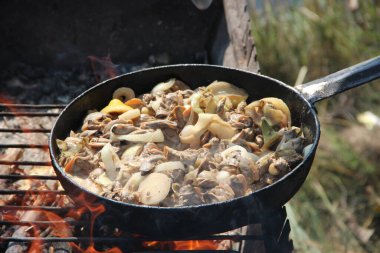Kızartma tavasında kızarmış midye pişirmek. Taze midye ve soğan kızartıyorum. Taze midye pişiriyorum. Kızarmış balığın tabağı ateşte pişiyor. Nehir kenarında iyi dinlenmeler. Yaz tatili