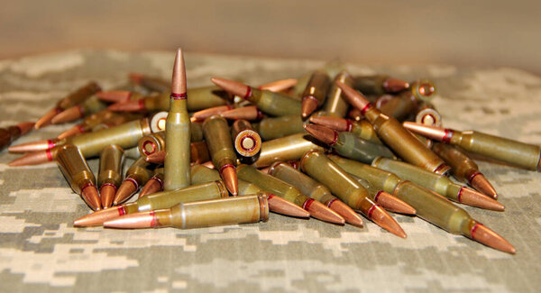 Cartridges for the Kalashnikov assault rifle. War Concept. Pile of cartridges with bullets. Means of killing. Ammunition for Kalashnikov assault rifle. Heap of billets