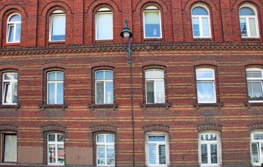 Birçok penceresi olan bir bina. Şehir manzarası. Şehir hayatı. Pencereli eski bir kırmızı tuğla bina. Şehir binasında birçok eşit pencere