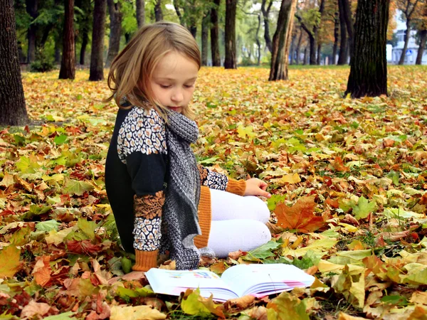 young girl reads a book in the autumn park