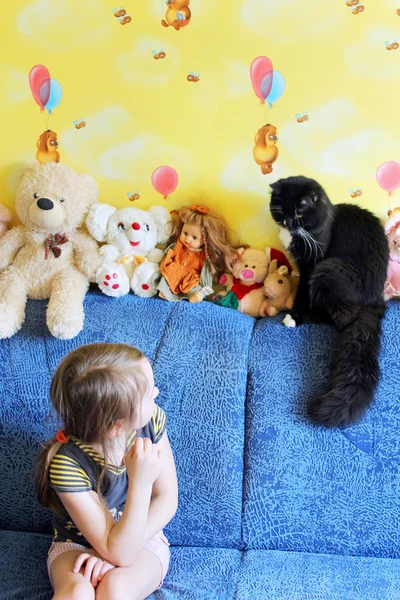 Meisje kijkt naar haar kat in de kinderkamer — Stockfoto