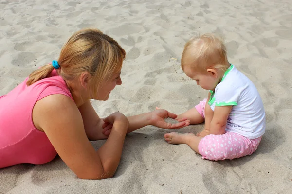 Happy mother play about with her baby on the sand — Stock Photo, Image