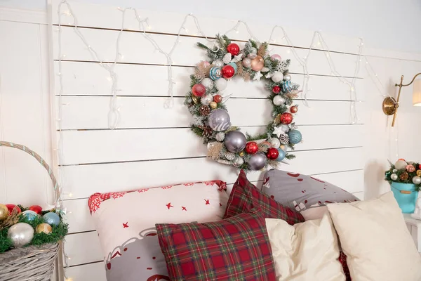 Christmas wreath made of fir branches, cones and Christmas toys on the wall.warm cozy modern design of the bedroom in bright colors decorated with Traditional hristmas wreath and decorative elements — Stock Photo, Image