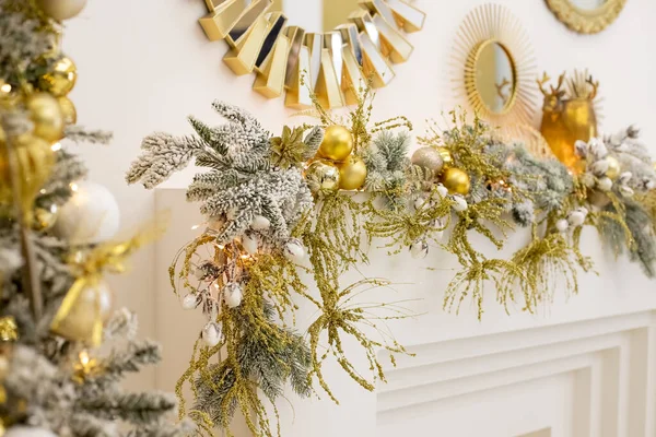 Luxury new year decor. Beige, golden, silver Christmas decoration. Merry Christmas and Happy Holidays. Festive interior with fireplace and decorations.golden baubles.Selective focus