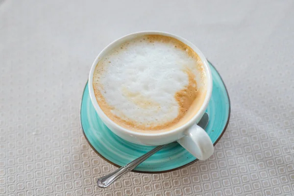 Gorąca kawa cappuccino sztuka latte w jadeitowym kolorze filiżanki izolowane na beżowym stole.Cappuccino filiżanka kawy widok z góry.Latte sztuki na mlecznej piance.Hot włoski napój energetyzujący serwowane w zielonej ceramicznym kubku — Zdjęcie stockowe