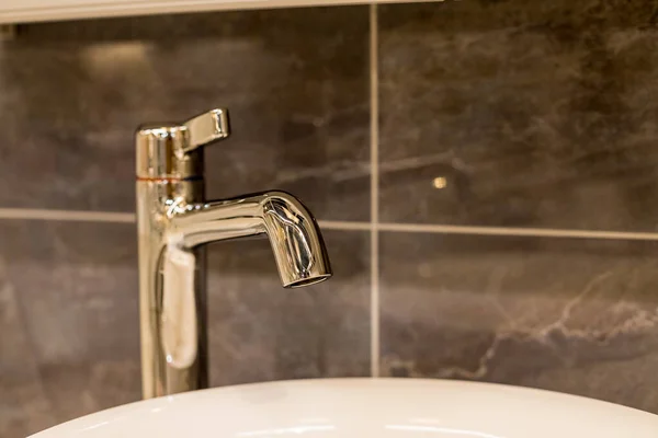 Mermer tezgahlı krom su musluğu ve beyaz lavabo. Güzel gri bir banyoda lüks bir musluk karıştırıcısı. Hijyenik önleme antivirüs kavramı. Seçici odak — Stok fotoğraf