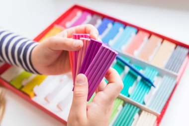 Gökkuşağı renkli plastik kutular beyaz arka planda izole edilmiş. Renkli çocuklar plastik, hamur modelleme çamuru. Küçük kız oyun hamurundan oyuncaklar yapmak istiyor.