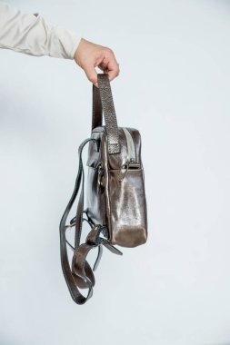 Sırt çantası, modaya uygun, şık aksesuarlar beyaz arka planda izole edilmiş. Kadın elinde bronz renkli çanta. Gezginler için el yapımı sırt çantası, günlük, okul, iş. Deri paketlerle şık alışveriş.