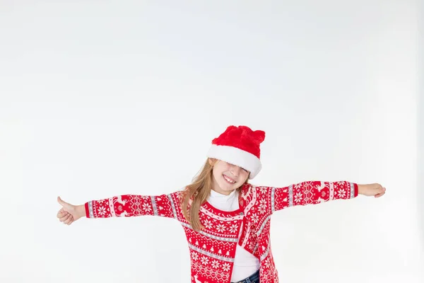 Lindo divertido ayudante de santas bailando sobre fondo blanco. Concepto de vacaciones de Navidad.Celebración de Año Nuevo. divertido bebé Santa.beautiful chica con sombrero de santa rojo celebrando el día de Navidad, divirtiéndose. — Foto de Stock