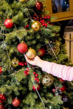 Noel ağacını Noel 'den önce süsleyerek süsleyen bir kız. Çocuk evi dekore ediyor. Çocuklu aile kış tatilini kutlar. İyi tatiller.