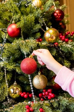 Noel ağacını Noel 'den önce süsleyerek süsleyen bir kız. Çocuk evi dekore ediyor. Çocuklu aile kış tatilini kutlar. İyi tatiller.