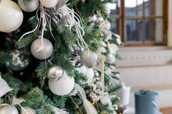 Ramo de árvore de Natal decorado com bolas de prata e decoração branca.Árvore elegante com bugigangas de prata e luzes na sala festiva. Árvore de Natal decorada moderna com bolas brancas, estrelas de prata e brinquedos. — Fotografia de Stock