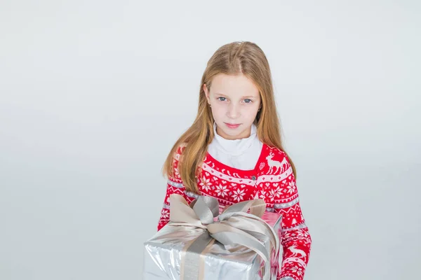 Милая девушка с рождественским подарком. Симпатичный ребенок, ребенок носит красный вязаный свитер в нордическом стиле с подарком, коробка празднует. С Новым годом, 2021. Счастливого Рождества! — стоковое фото