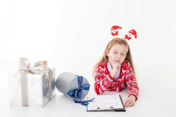 Рождественская распродажа Мбаппе удивил ребенка, держа в руках ручку и написав на белом фоне. Мечтающий ребенок с письмом для Санта Клауса и составить список желаний на Новый год. Эмоции. — стоковое фото
