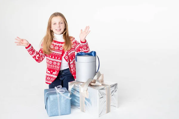 Красивая маленькая девочка в рождественском свитере сидит изолированы на белом фоне, держа стопку подарков boxes.Merry рождественские подарки магазины sale.Holidays Атмосфера. — стоковое фото