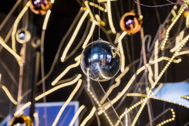 Peri ışıklarının arka planında asılı Mutlu Noeller süsleri. Karanlık iç kısımlarda parlak Noel topları. Tatil kavramı. Yeni yıl için alternatif, yaratıcı dekorasyon..