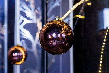 Peri ışıklarının arka planında asılı Mutlu Noeller süsleri. Karanlık iç kısımlarda parlak Noel topları. Tatil kavramı. Yeni yıl için alternatif, yaratıcı dekorasyon..