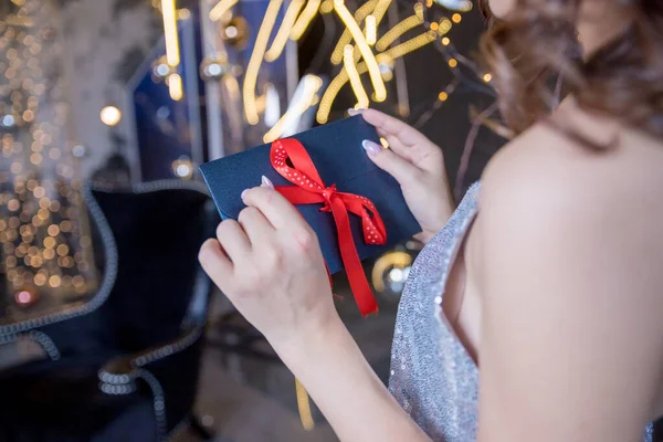 Fiatal boldog lány nyitó karácsonyi kártya.Nevető játékos fiatal nő kezében egy dekoratív boríték kötve piros szalaggal. Ünnepi ünnepi koncepció.Boldog fiatal nő nyitó karácsonyi levél — Stock Fotó