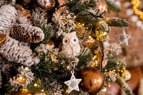 Árvore de Natal festiva com coruja branca, cones de pinho em ramos de abeto. Brinquedo de Natal, coruja no ramo de árvore de Ano Novo, em torno de bolas de prata e ouro, fundo borrado. — Fotografia de Stock