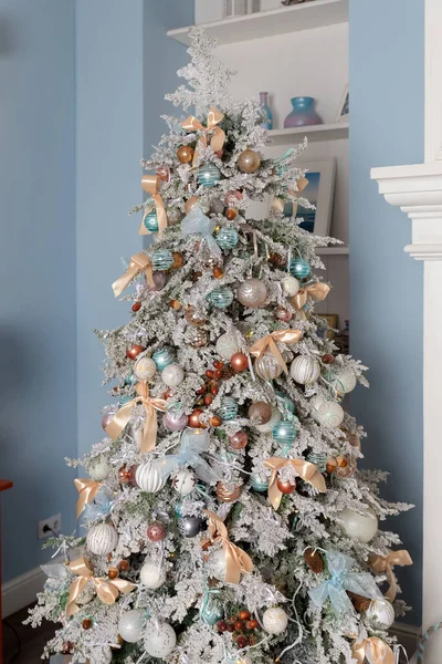 Красивые рождественские подарки под елкой в новогоднем украшенном интерьере дома. Комната украшена к празднованию Рождества, елка с различными формами, разноцветные шары, декоративные луки блеска, орехи. — стоковое фото
