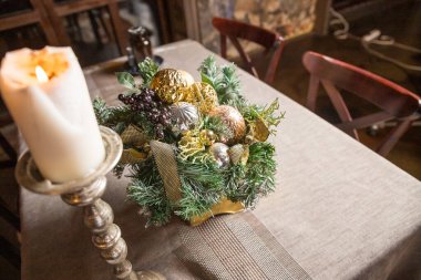 Noel mumu ve süslemeler fotokopi alanı olan masada. Klasik dekor, sepetteki süslemeler, fenerler, çelenkler, beyaz bir masa üzerindeki ladin dalları. Noel için İskandinav oturma odası detayları..