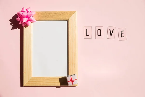 Wenskaart voor Valentijnsdag. Vakantie mock up, harten op pastel roze achtergrond. Liefdesbericht.Moederdag, Huwelijksuitnodiging. houten frame versierd met strik en cadeautjes, kopieerruimte — Stockfoto