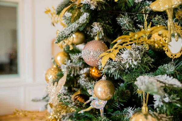 装饰圣诞树，装饰着金色的装饰品，白色的玻璃球和礼物，作为新年的礼物。家居装饰，带有花环的圣诞树，灌木，传统的庆祝活动. — 图库照片