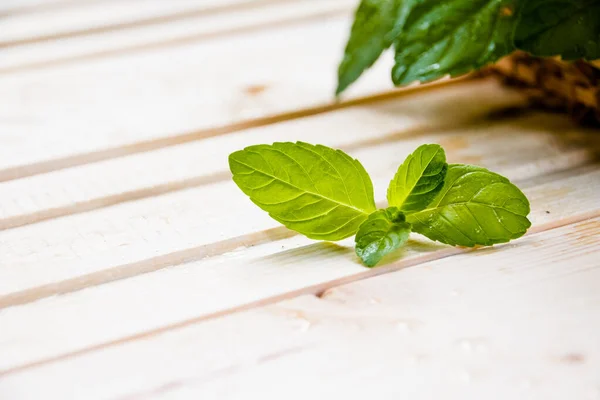 Fresh mint in bowl on wooden table. Selective focus.Peppermint in small basket on natural wooden background,Mint leaves under sun rays.Copy space — Stock Photo, Image