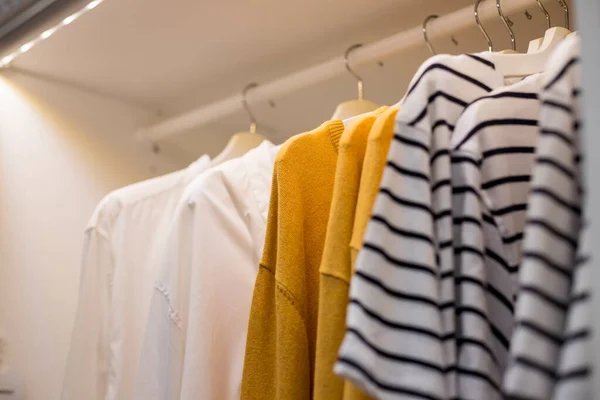 Many blouses,shirts on hangers in the dressing room.Modern wardrobe with stylish spring clothes and accessories.Rack with different clothes in a shop or home closet — Stock Photo, Image