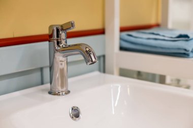 Banyo içi beyaz lavabo ve muslukla dolu. Krom banyo musluğu. Modern tasarım. Zarif banyoda lavabonun ayrıntıları. Musluk suyu.