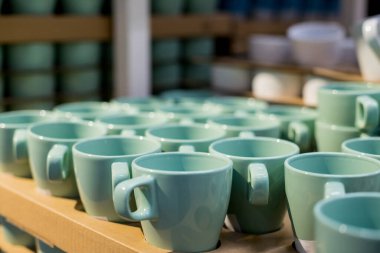 Boş seramik fincanların arka planı. Mağazadaki raflarda beyaz ve mavi bardaklar. Kahve bağımlılığı ve çanak çömlek ürünleri kavramı.