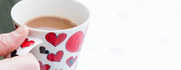 Young man in coat drinking a hot drink. Tea cup with a red hearts.Foggy snowy weather,cup with coffee in male hands on the background of a winter. Red hearts, love.Winter season. Coziness. — Stock Photo, Image