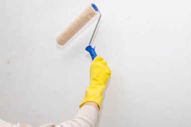 Boya patenli eldivenli işçinin eli evin içinde duvarları boyuyor. Evdeki Tamir. onarım ve bakım kavramı