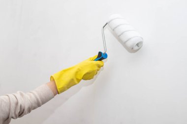 Boya patenli eldivenli işçinin eli evin içinde duvarları boyuyor. Evdeki Tamir. onarım ve bakım kavramı