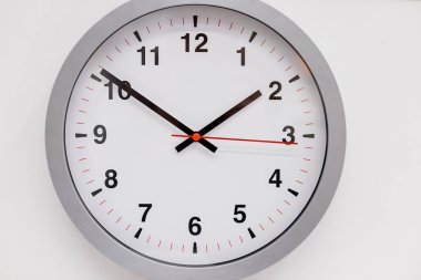 Gümüş renkli çerçeveli basit modern duvar saati, beyaz arka planda izole edilmiş. Evin içi. Duvarda asılı büyük yuvarlak bir saat. kopya alanı, son teslim tarihi, zaman yönetimi kavramı ve öğle yemeği zamanı.