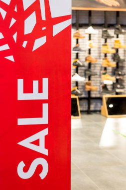 Alışveriş merkezinin girişindeki hırsızlıkla mücadele sensöründe parlak kırmızı pankart. Mevsimlik indirim teklifi. Mağaza girişinde indirim bilgileri, alışveriş sezonunun tanıtımı. Büyük kırmızı paneller..